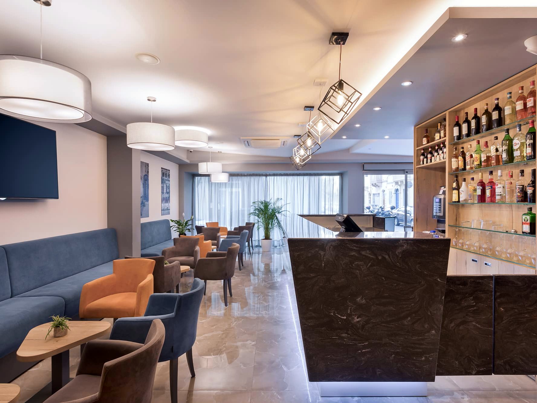 Salon-bar du hall de l’Azur Hotel by ST Hotels avec comptoir, banquette et fauteuils