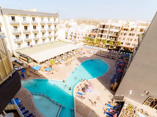 Vue plongeante sur la piscine extérieure du Topaz Hotel, sa terrasse, ses transats et ses parasols