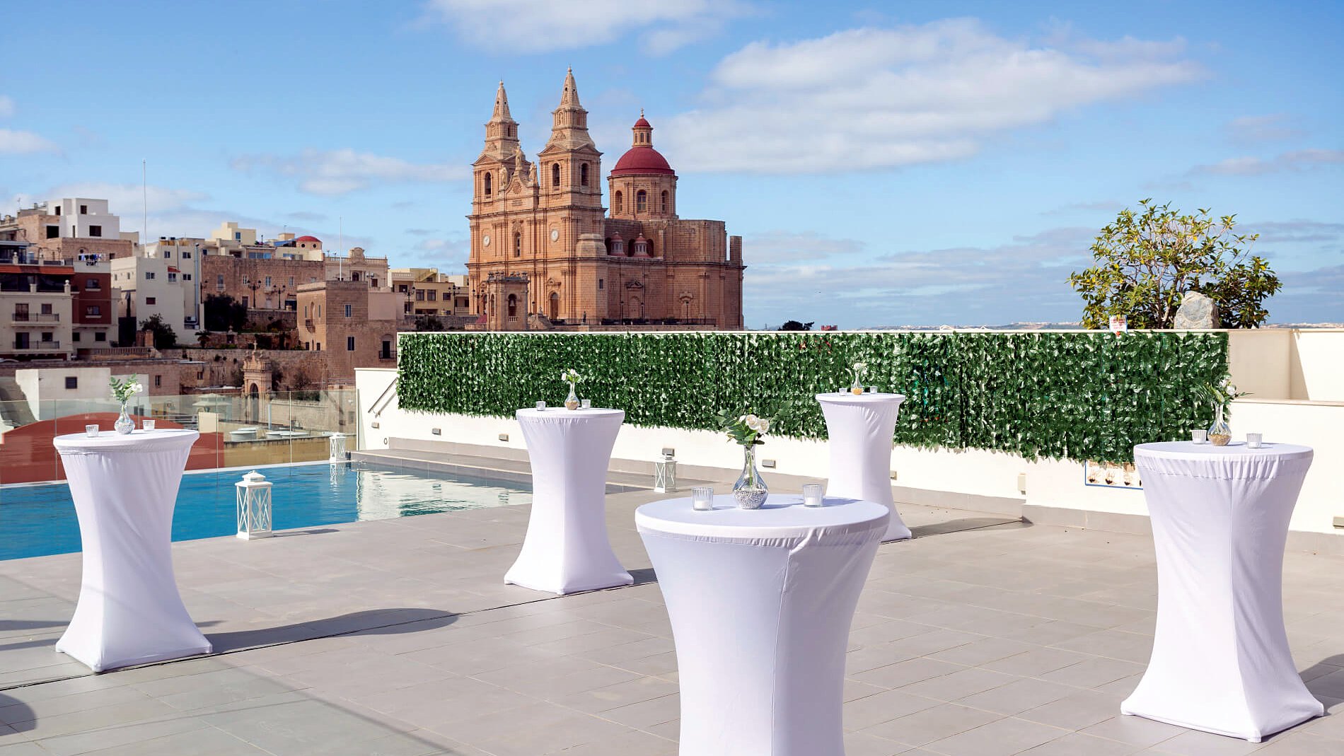Terrazza sul tetto del Pergola Hotel & Spa a bordo piscina, con vista sulla chiesa di Mellieħa