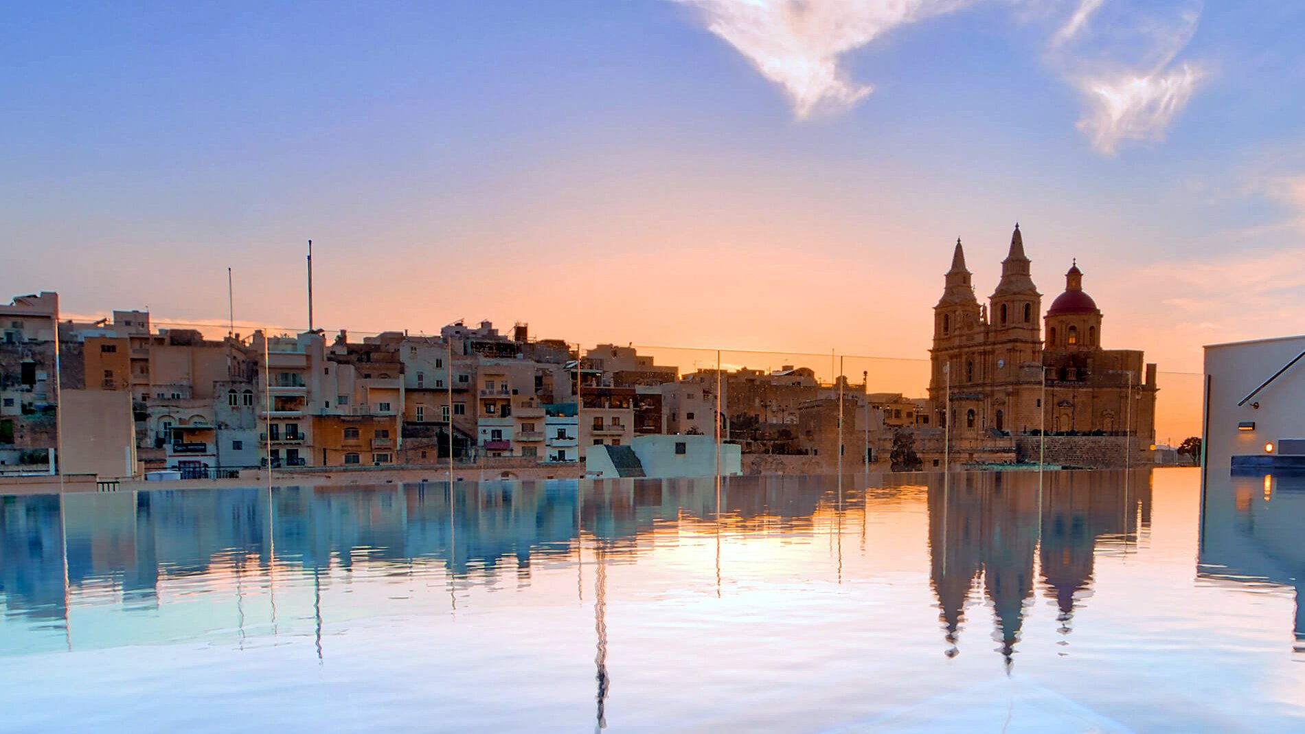 Piscina a sfioro sul tetto del Pergola Hotel & Spa al tramonto, di fronte alla chiesa di Mellieħa