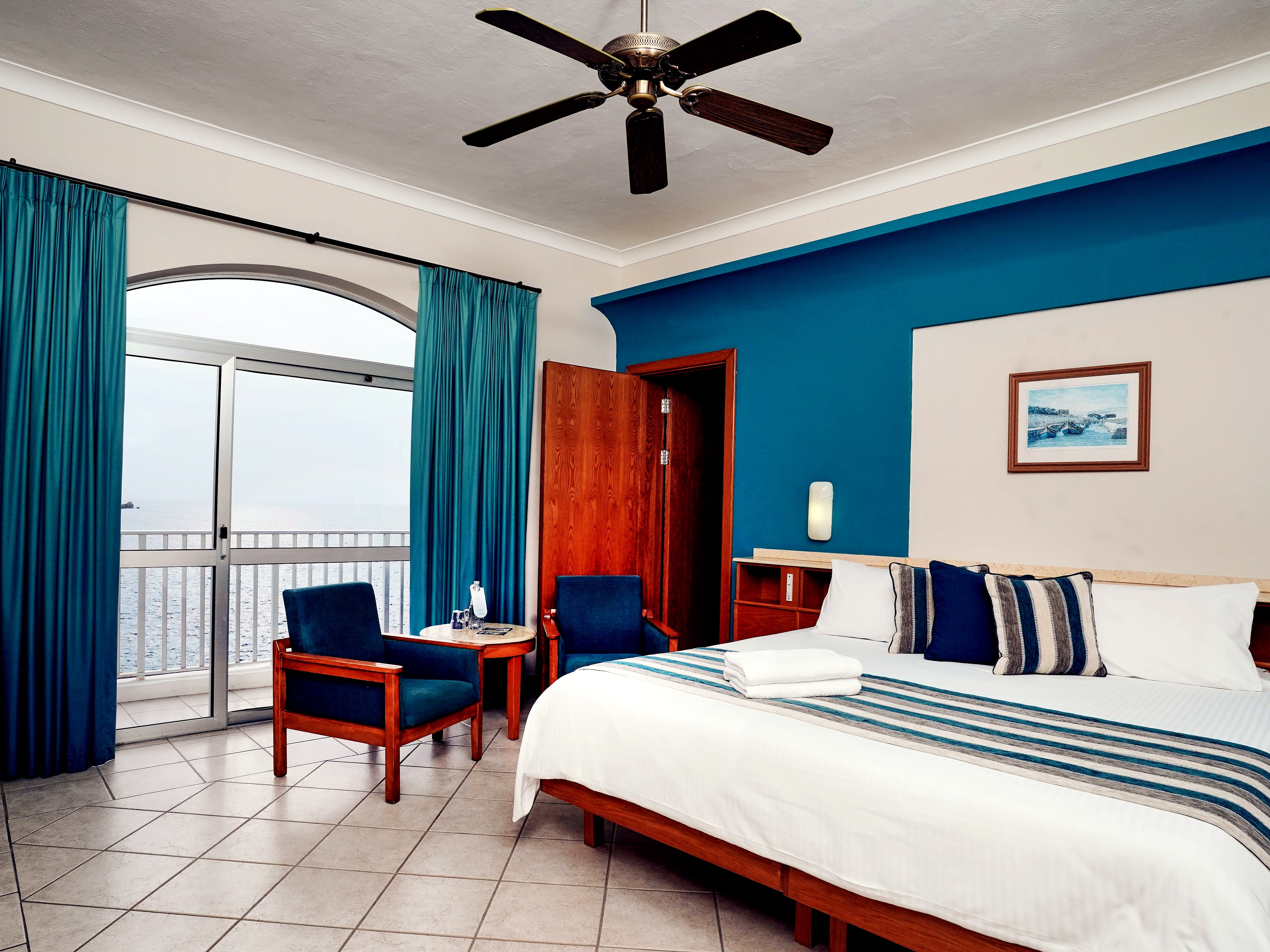 Camera vista mare del Paradise Bay Resort con letto matrimoniale, parete blu e balcone sul mare