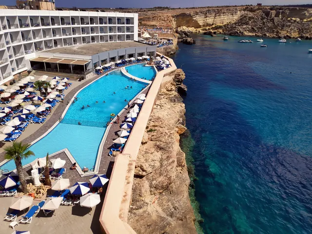 Piscine extérieure du Paradise Bay Resort bordée de transats, au bord des falaises et de la mer