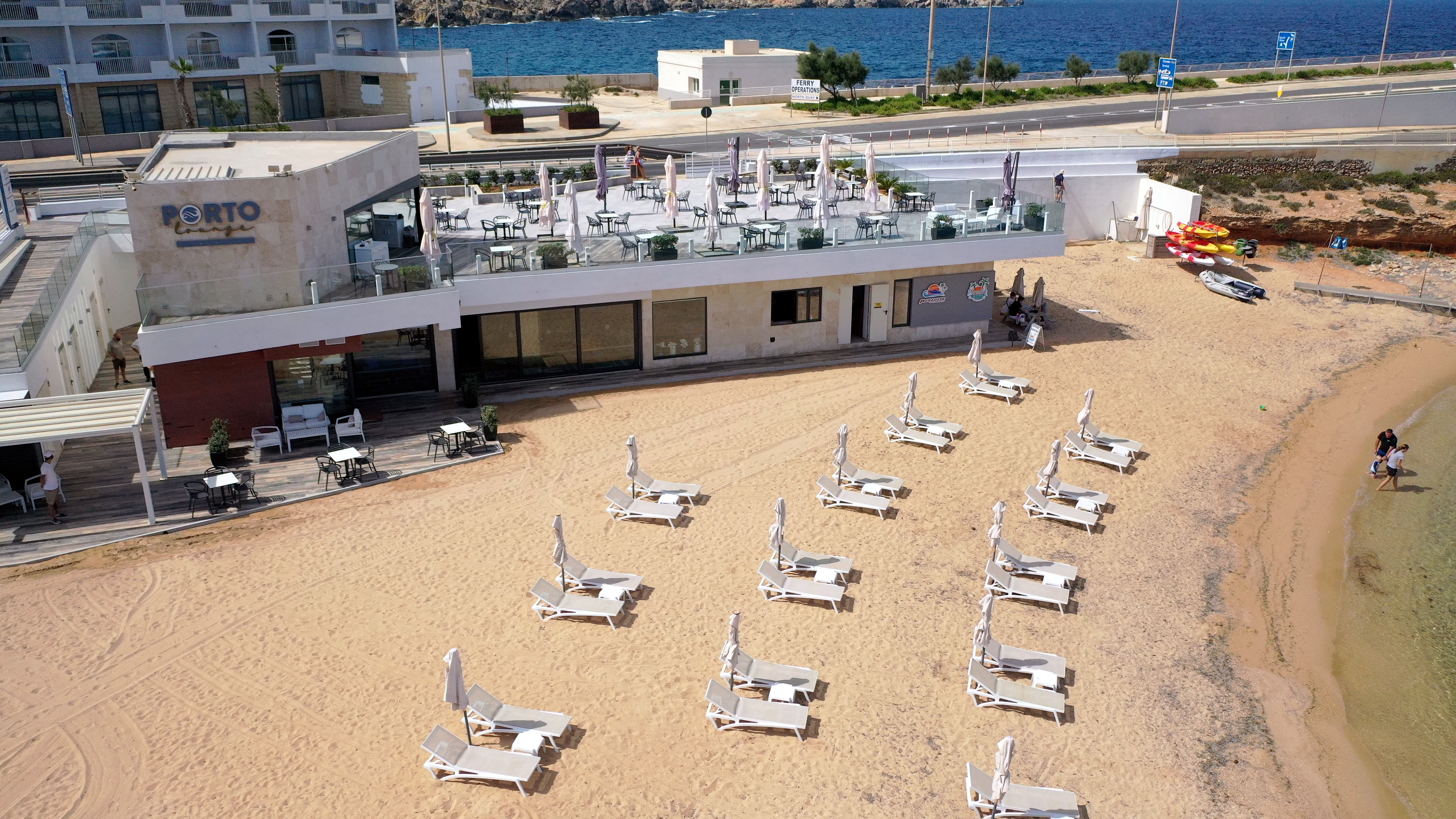 Spiaggia privata di sabbia del Paradise Bay Resort con lettini e ombrelloni, ai piedi del Porto Lounge