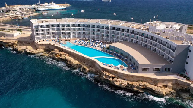 Vue aérienne du Paradise Bay Resort à Ċirkewwa, avec sa piscine sur les rochers et le port du ferry pour Gozo