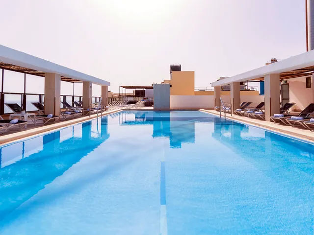 Piscine extérieure sur le toit de l’Alexandra Hotel à St Julian’s, bordée de transats sous des pergolas
