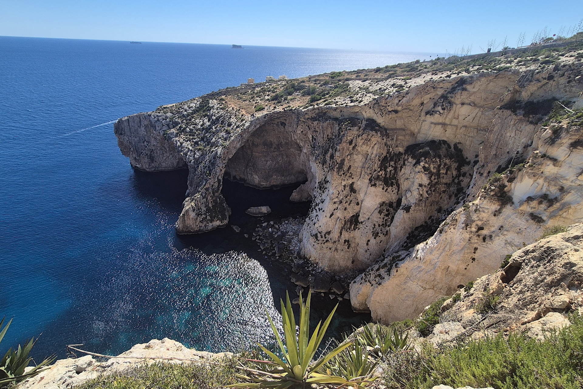 Arco natural e falésias calcárias da Blue Grotto vistos do alto, sobre o mar azul em Malta