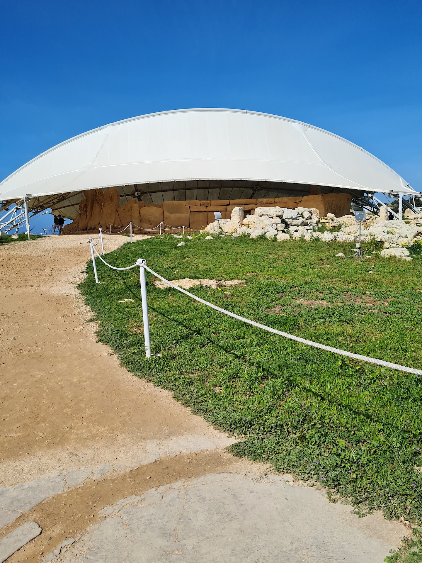Extérieur du temple de Ħaġar Qim et son abri Vue extérieure du temple de Ħaġar Qim à Malte, couvert de son abri blanc, avec un sentier menant à l’entrée