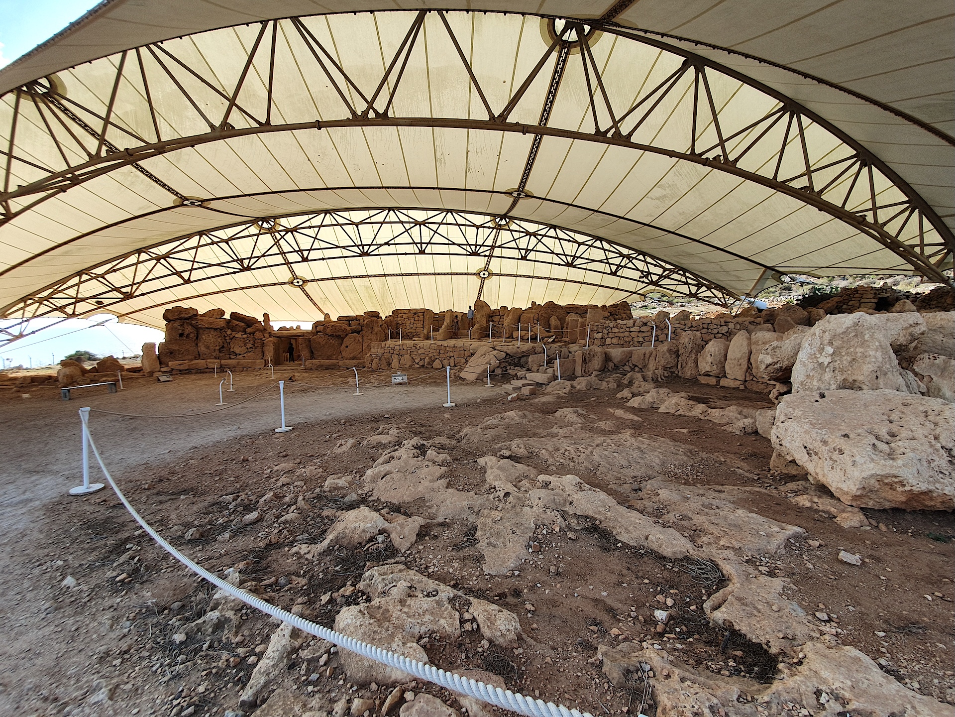 Vestiges du temple de Ħaġar Qim sous l’abri de protection Vue d’ensemble des vestiges du temple préhistorique de Ħaġar Qim, abrités sous une vaste tente de protection blanche, à Malte