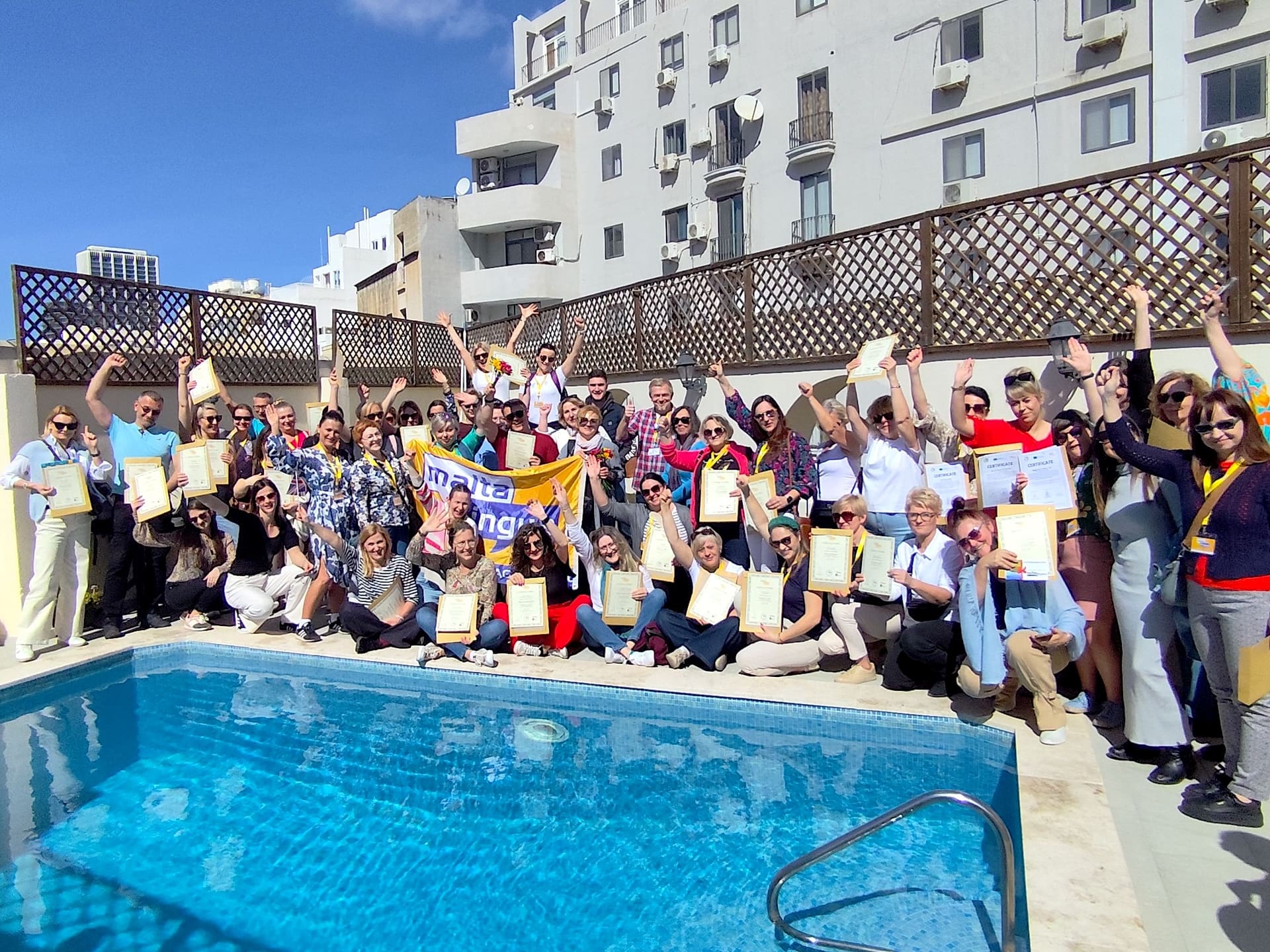 Studenti di Maltalingua con i certificati attorno alla piscina sul tetto