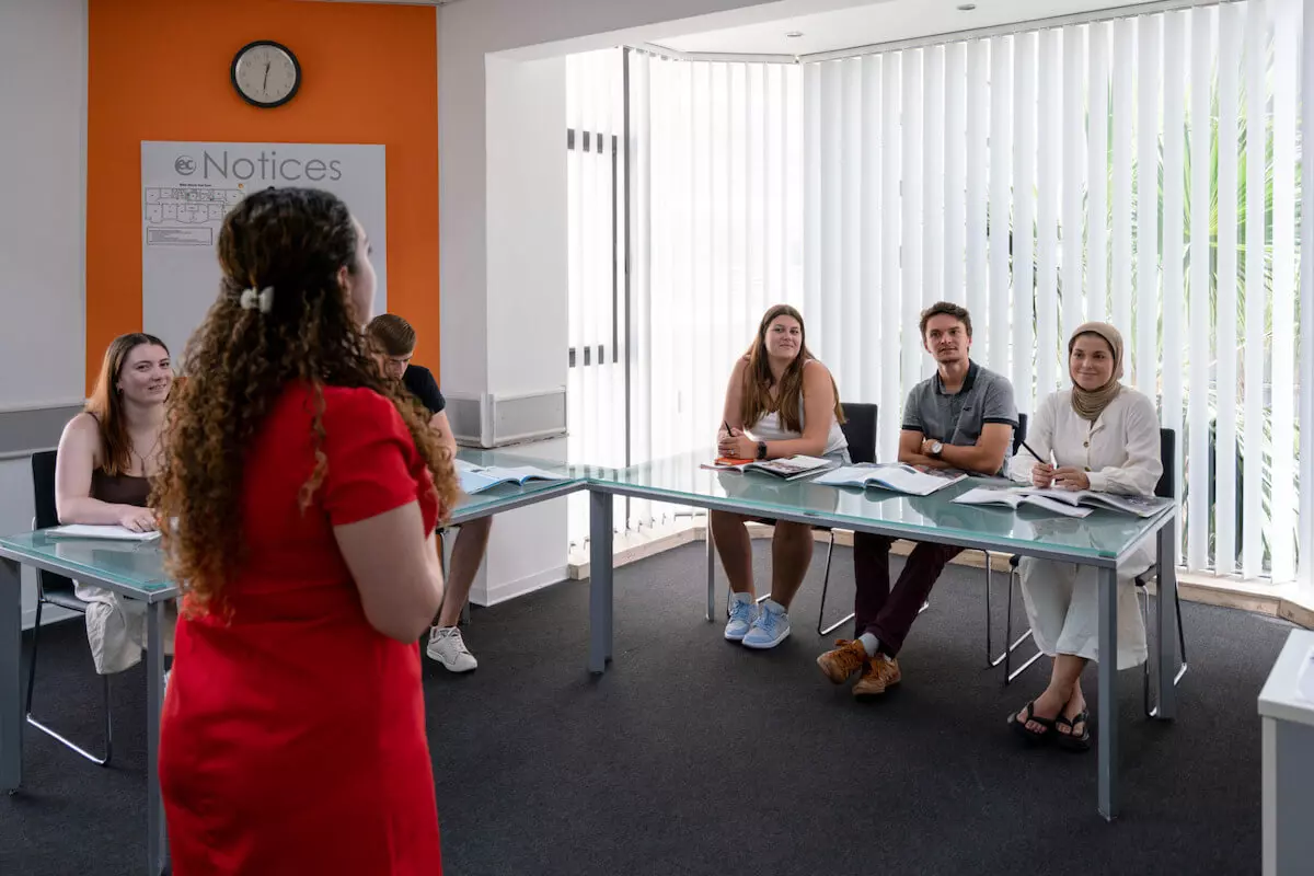 Une professeur de dos donne un cours à des étudiants de l'EC Malte