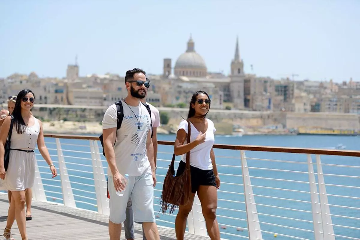 Pequeno grupo de estudantes caminhando à beira-mar em frente a La Valette