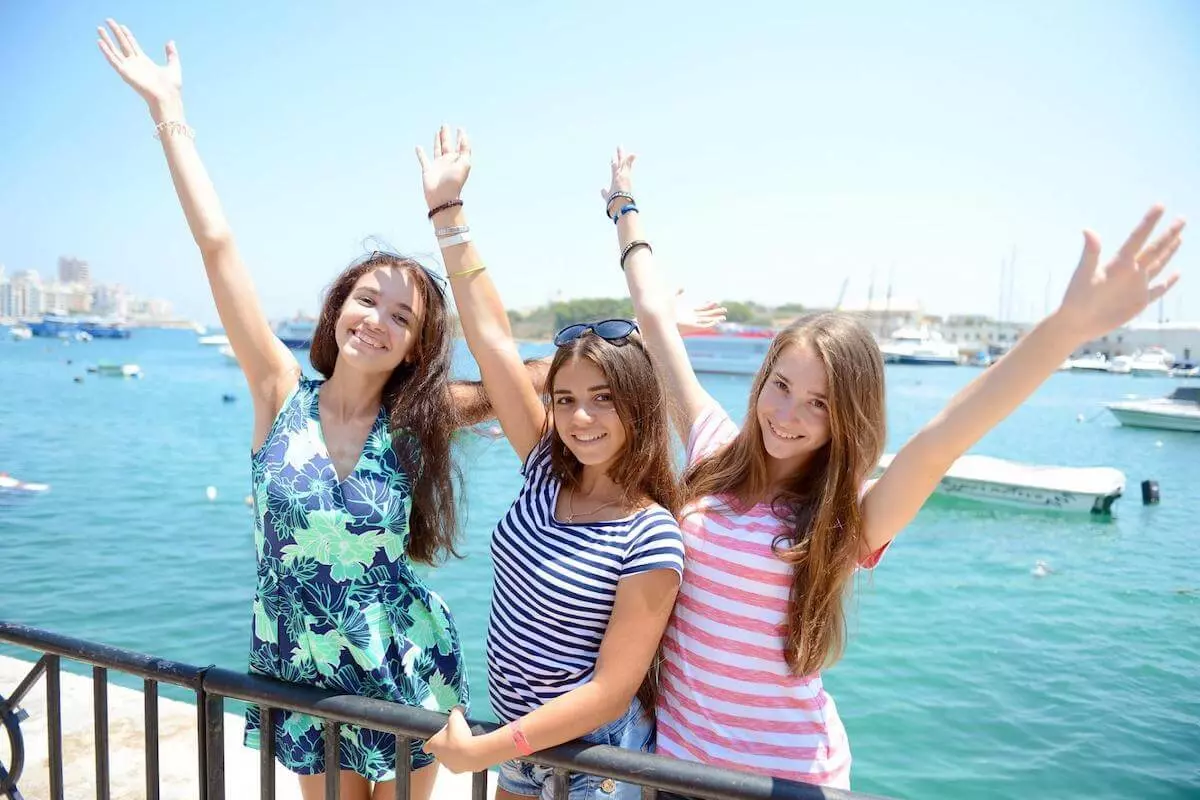Three young female students standing by the sea in Malta