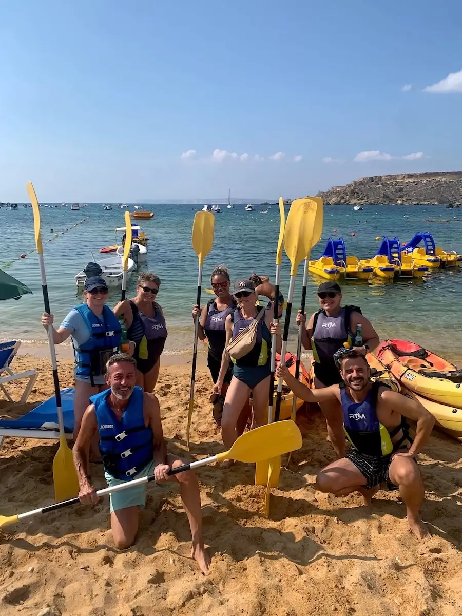 Siete adultos con remos frente a kayaks