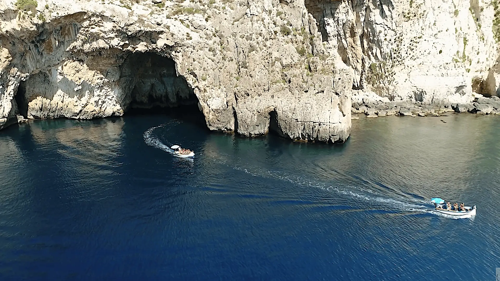 Two boats exiting the arch of Blue Grotto in Malta