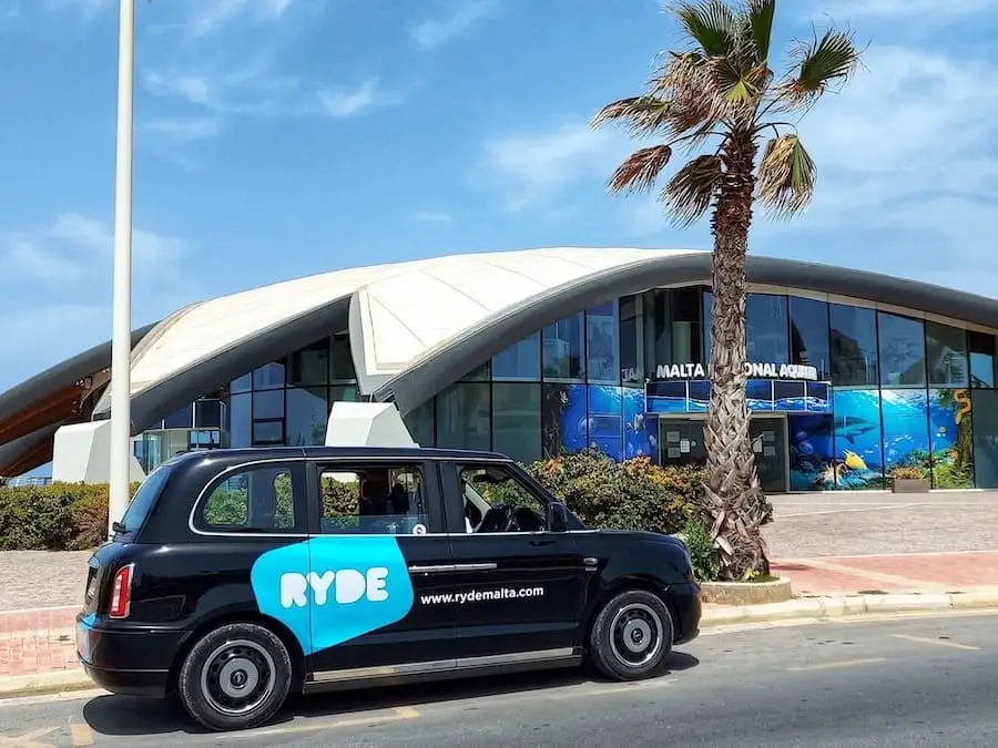 Ryde Malta Auto nera in stile taxi inglese di Ryde davanti all'acquario di Malta