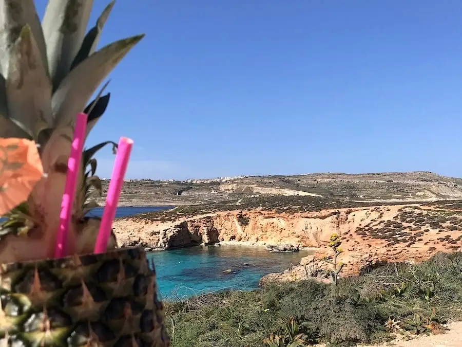 Cocktail all'ananas alla Blue Lagoon Cocktail all'ananas con la Blue Lagoon di Malta sullo sfondo