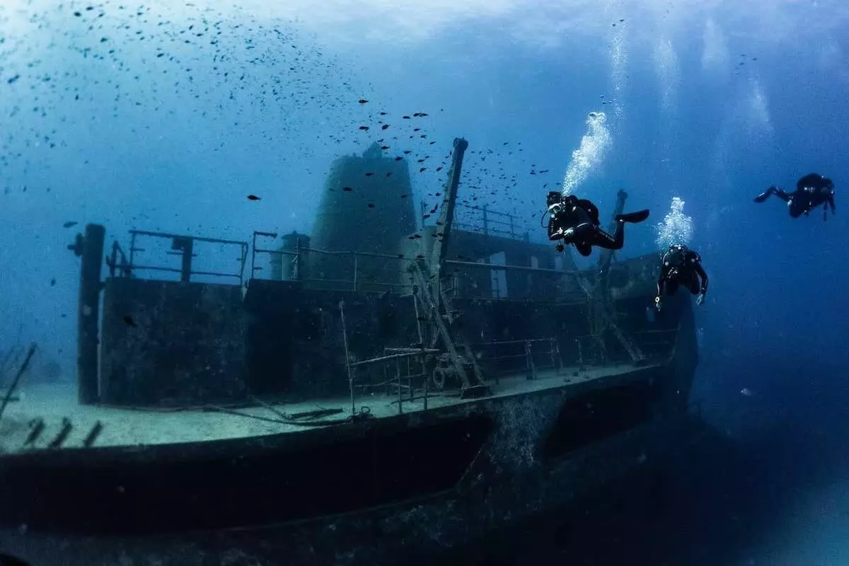 3 divers near an underwater wreck in Malta