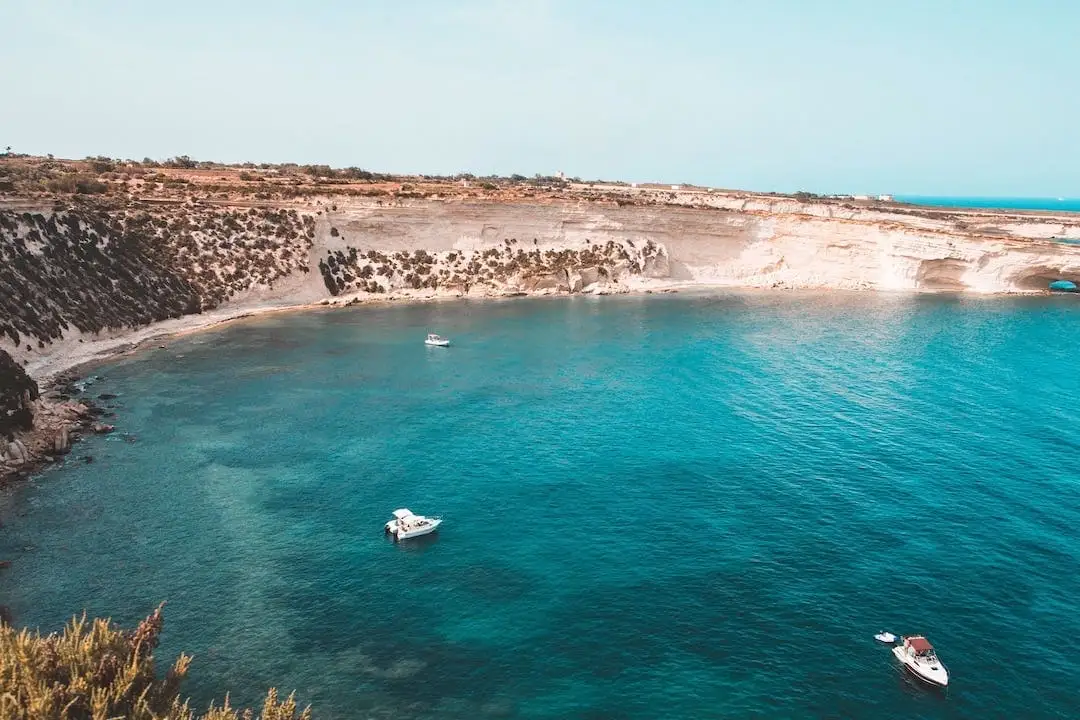 Enseada com três pequenos barcos em Malta