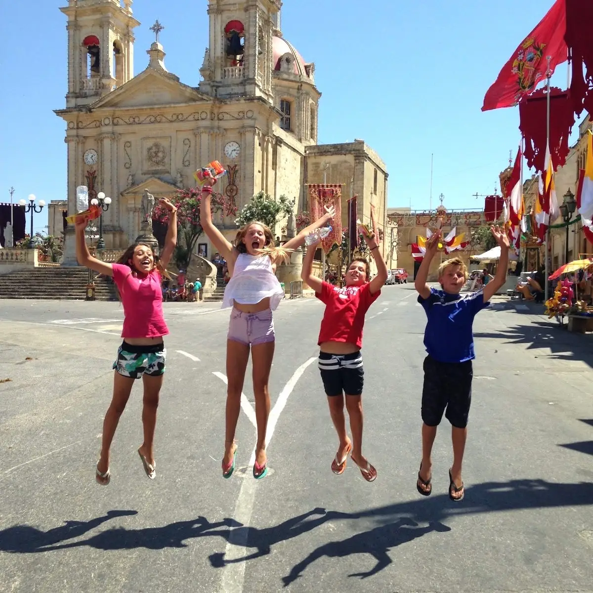 Adolescents en séjour linguistique à Malte 4 adolescents en séjour linguistique qui sautent devant une église à Gozo