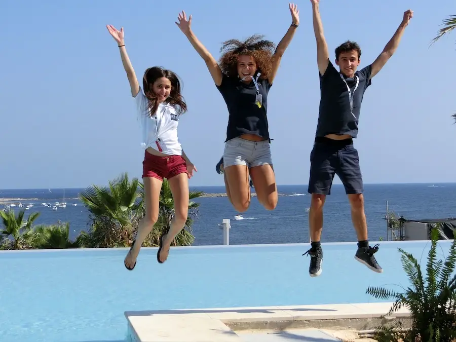Trois encadrants des séjours linguistiques à Malte pour jeunes sautant devant la piscine du Salini Resort