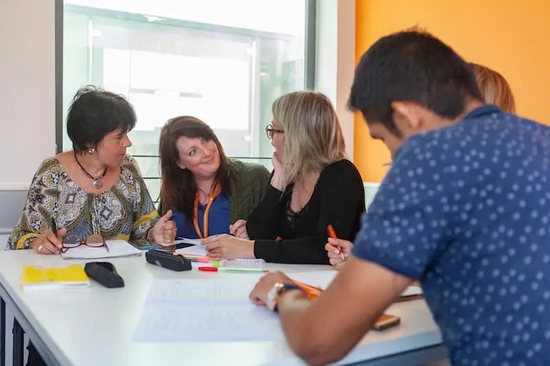 4 estudiantes adultos y su profesor en clase de inglés