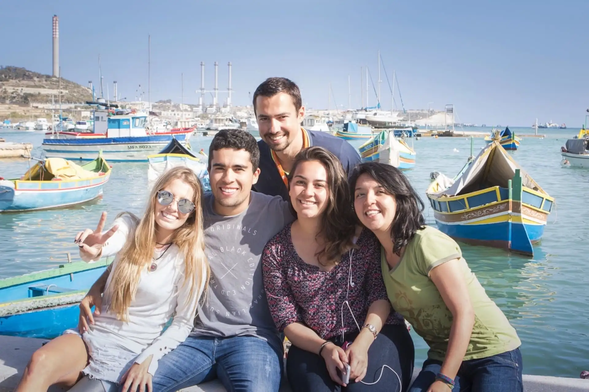 Group of students at Marsaxlokk in front of traditional Maltese boats