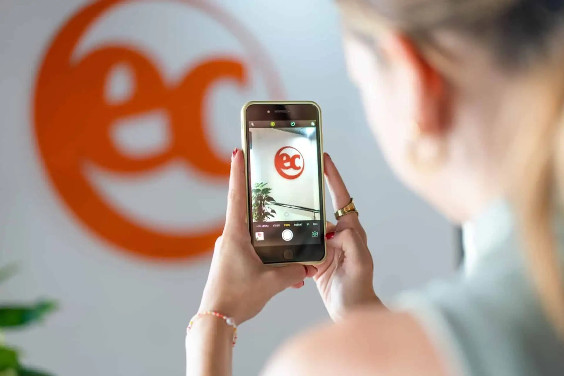 Student taking a photo of the EC Malta logo with her phone